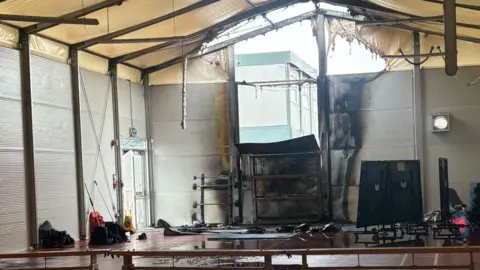 Carley James A temporary sports hall which is similar to a large marquee has one end damaged by the fire. 