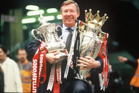 Getty Images Sir Alex Ferguson with the FA Cup and Premiership Trophy at Victoria Station, Manchester, on 12 May, 1996 after completing The Double