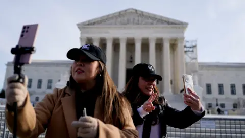 Two women holding up phones outside the Supreme Court in Washington DC.