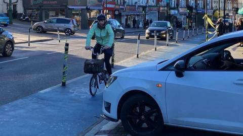 A cyclist pedals along the bike lane in front of a T-junction