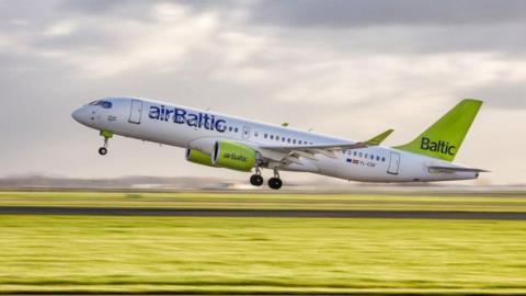 An airBaltic A220 plane taking off from a runway
