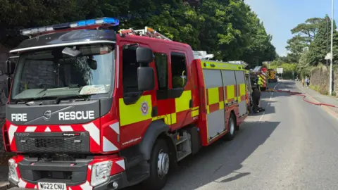 AB Coaches Ltd A row of fire engines on a road with a red hose across the road.