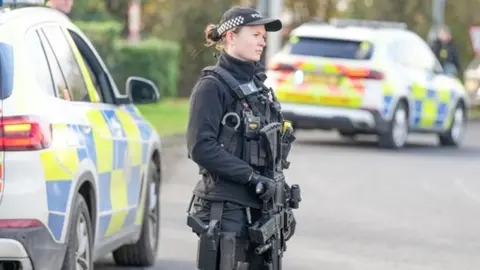 Eddie Mitchell Female police officer holding a gun outside Gatwick Airport. 