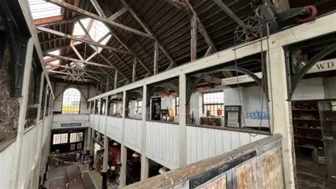 Shaun Whitmore/BBC The inside of the museum. Two floors can be seen and in the roof wooden beams have been constructed. Exhibitions and artefacts can be seen dotted around the different levels. 