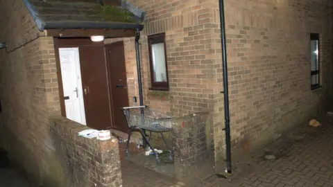 South Wales Police/ CPS A brown-brick house with white PVC door and a shopping trolley outside