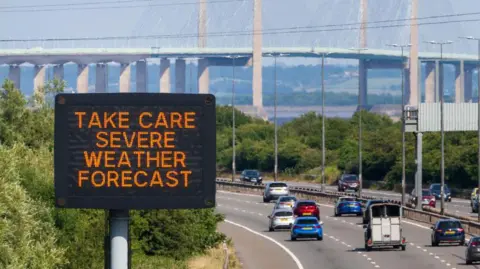 Heat warning matrix sign with the Severn Bridge in the background