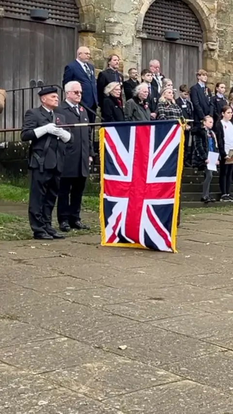 A man holding a Union flag observes a two-minute silence