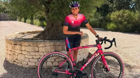Michelle Sharland Michelle Sharland standing with her bike in front of an olive tree 