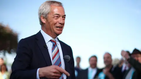 EPA Nigel Farage speaking to Reform UK supporters. He is wearing a white shirt and navy blazer, and a red, white and blue tie. He has grey hair.