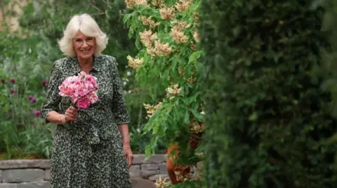 PA Media Queen Camilla holds roses called "The King's Rose", of David Austin Roses, during a visit to the RHS Chelsea Flower Show, at the Royal Hospital Chelsea in London