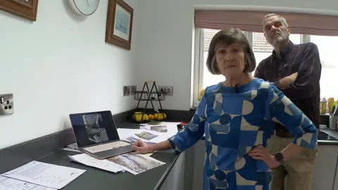 BBC David and Anne Strobel together looking at photographs of water damage