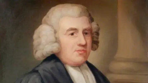 Cowper and Newton Museum Painted portrait of John Newton wearing an 18th-century white powdered wig and a dark robe over a white neck cloth. The figure is shown from the chest up, facing slightly to one side against a muted background with a stone column visible on the right. The portrait uses soft tones and traditional oil-painting style.