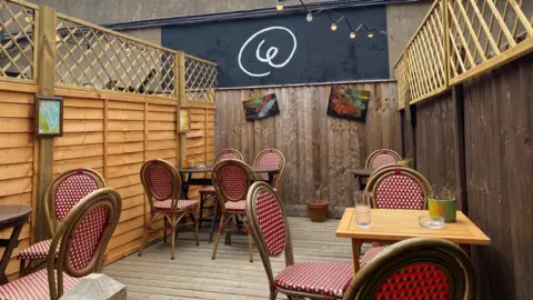 An outdoor area with gingham patterned chairs and fairy lights