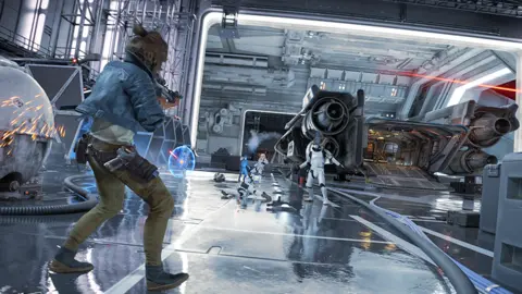 Ubisoft A still from Star Wars Outlaws, with one character wearing a blue denim top and green combat trousers - shooting towards another.