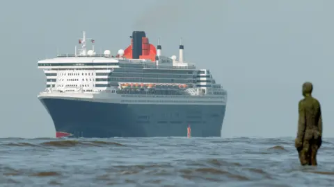 Cunard's Queen Mary 2 sails past Antony Gormley's Another Place on the approach into Liverpool