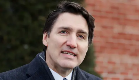 Close-up photo of Trudeau outside, showing him in a dark grey coat with a brick building in a blur behind him