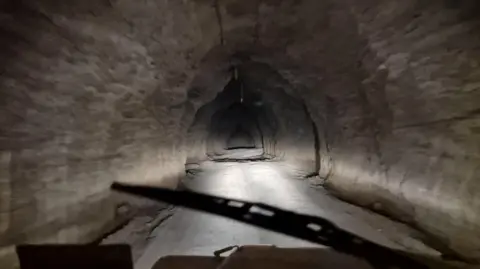 One of the tunnels leading into the depths of Birkshead drift mine. The image has been taken from inside a vehicle, looking out to the tunnel.