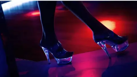 A pair of feet in some transparent platform heels standing on what appears to be a stage