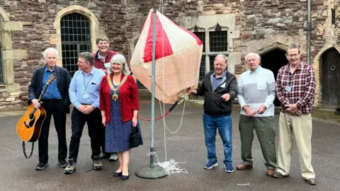 BBC Seven people stood around a replica of the balloon at Berkeley Castle