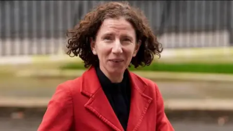 PA Media MP Anneliese Dodds wearing a red coat and black top. She has short curly brown hair.