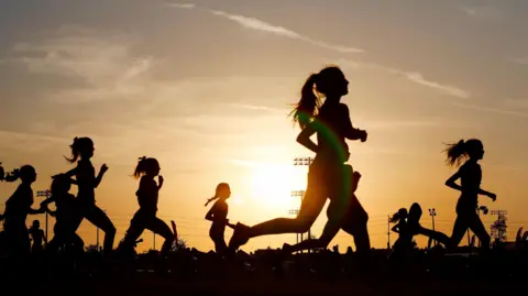 A group of people running at sunset.