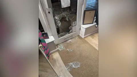 Contributed A photo of a shop front door where the window has been broken and smashed at the bottom. Shards of glass rest on the floor inside the store. 