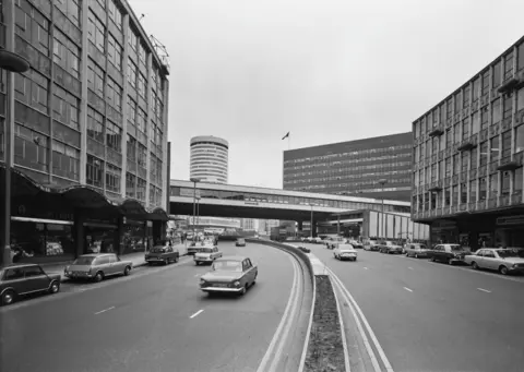 Getty Images A black and white image of Birmingham's Ringway Centre in the 1970s, with cars seen driving down the wide route. The city's rotunda tower can be seen in the background with cars parked on either side of the road. 