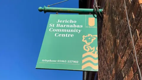 A green sign is in front of a blue sky. It says Jericho St Barnabus community centre