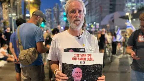 Lee Siegal holds poster showing his brother Keith's photo 