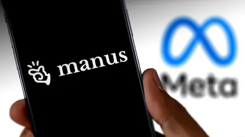 A hand holds a smartphone displaying the Manus company logo, against a backdrop of the blue and back Meta logo.
