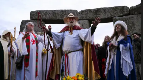REUTERS/Jaimi Joy Men and women in robes look spiritual and stand in front of stones. A man in front raises his arms.