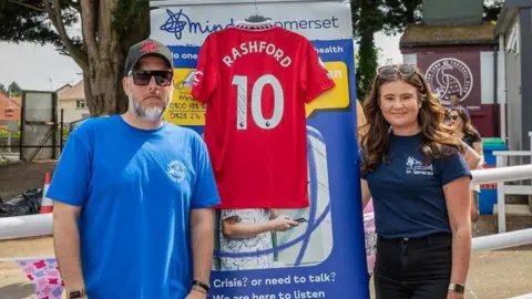 Dan James Man and woman looking at camera in front of billboard