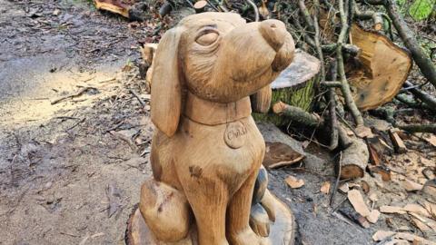 A sitting cartoon dog carved out of tree trunk