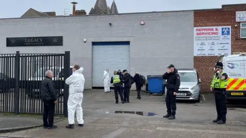PA Media Police and forensic officers, wearing white suits, stand outside Legacy Independent Funeral Directors off Hessle Road in Hull.