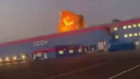 A screengrab from a video on social media showing flames rise from an Ozon facility following a Ukrainian drone strike in Makhachkala, Dagestan, Russia.
