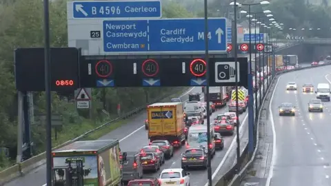 A motorway in Newport with blue signs indicating that drivers should be in the left hand lane for Newport and Cwmbran, and the right two lanes for Cardiff.