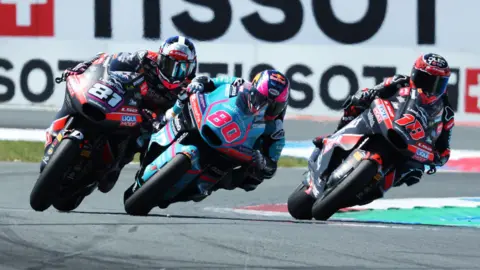 Reuters Three motorbike riders go round a corner on a racing circuit. 