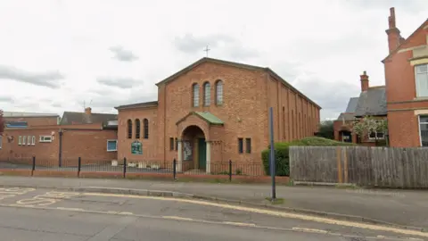 Google A Google Streetview of St Peter's Church in Rushsden. It has an apex roof with a cross on top and and a porch area.