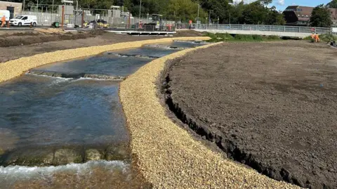 Environment Agency A river flowing down in steps over a gentle gradient, shallow rock steps