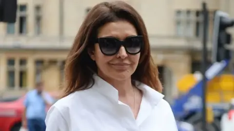 PA Media A picture of Zamira Hajiyeva, who has shoulder-length brown hair and is wearing sunglasses, walking along an unknown street.