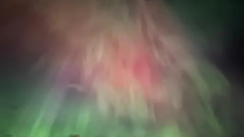 BBC Weather Watchers / Rossi Night sky with white whispy streaks mixed in with purples and greens of the aurora.