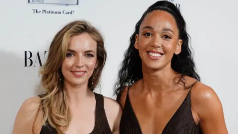Jodie Comer and Katarina Johnson-Thompson pictured together at an awards ceremony where they are both wearing black dresses and smiling at the camera