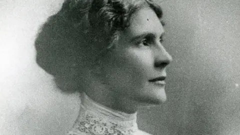 Leeds City Council A black and white photograph of a woman's side profile. She has tied up curled hair and is wearing white lace.