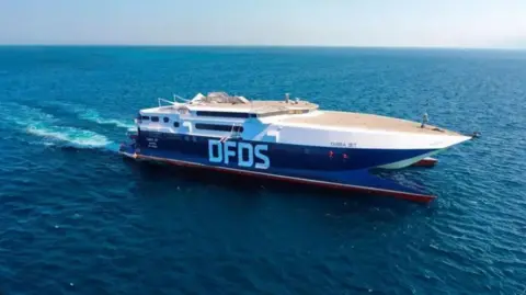A DFDS ferry with dark blue livery, sails across the sea
