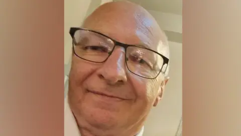 Family handout Photograph of Bernard Payne. He is smiling, bald and is wearing dark-rimmed glasses.