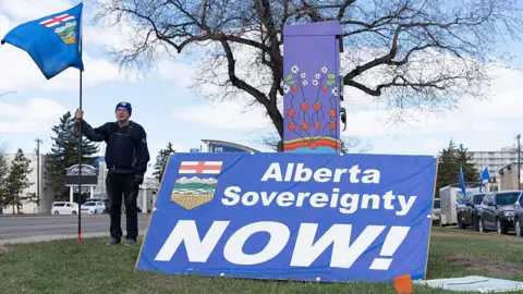 A separatist supporter holds a flag during a rally near the Elections Alberta headquarters in Edmonton, Canada, on May 4, 2026, as they submit boxes of signatures in the hope of triggering an independence referendum