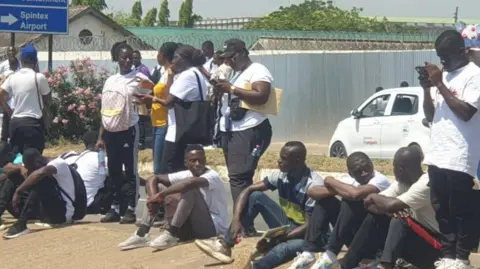 BBC A group of young people sit on the ground