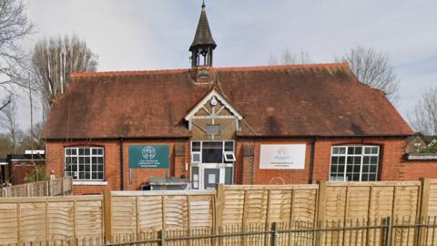 A Google streetview of the Leatherhead Community Hub and All Saints nursery which is a redbrick building with a small spire