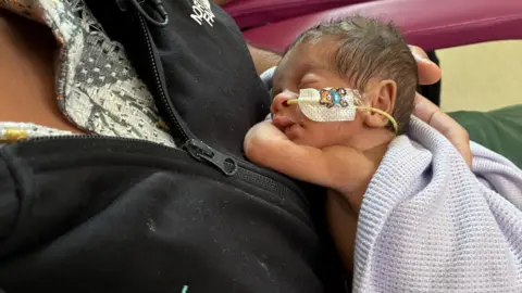 A tiny baby sleeps on his father's chest