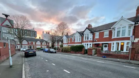 A street in Cardiff with cars parked on both sides of the road 
